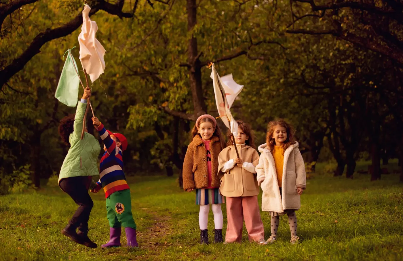 Children waving homemade flags in an autumn park