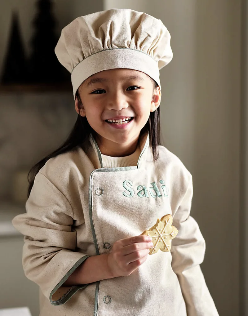 A child in a chef hat at a bakery counter